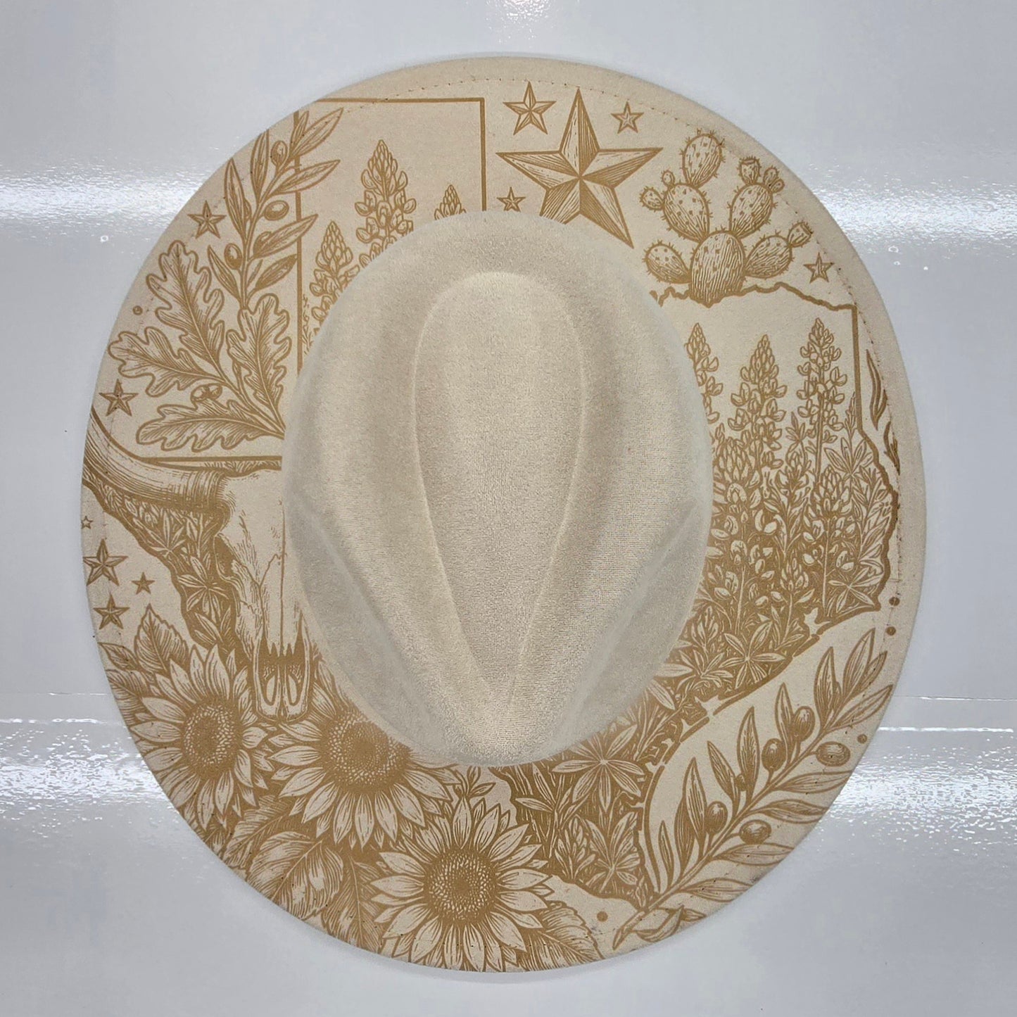 Cream cowboy hat with decorative brown patterns on a white background