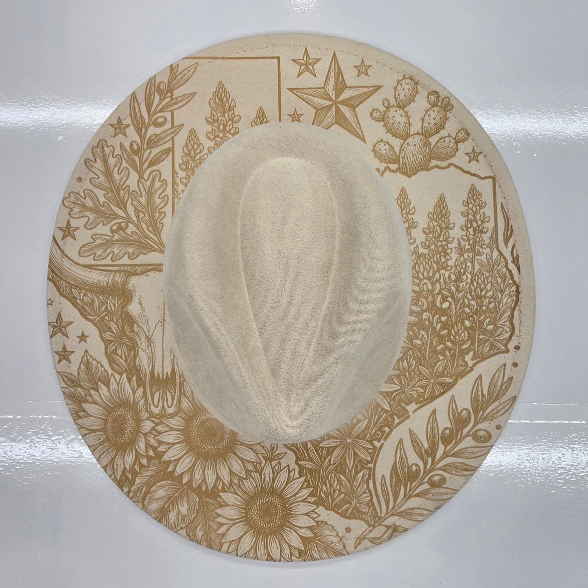 Cream cowboy hat with decorative brown patterns on a white background